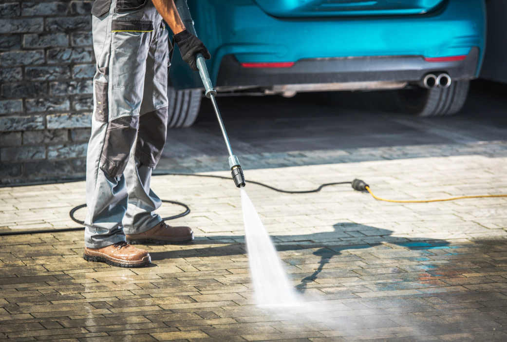 Man directing water at moldy stone driveway in Mills River, NC